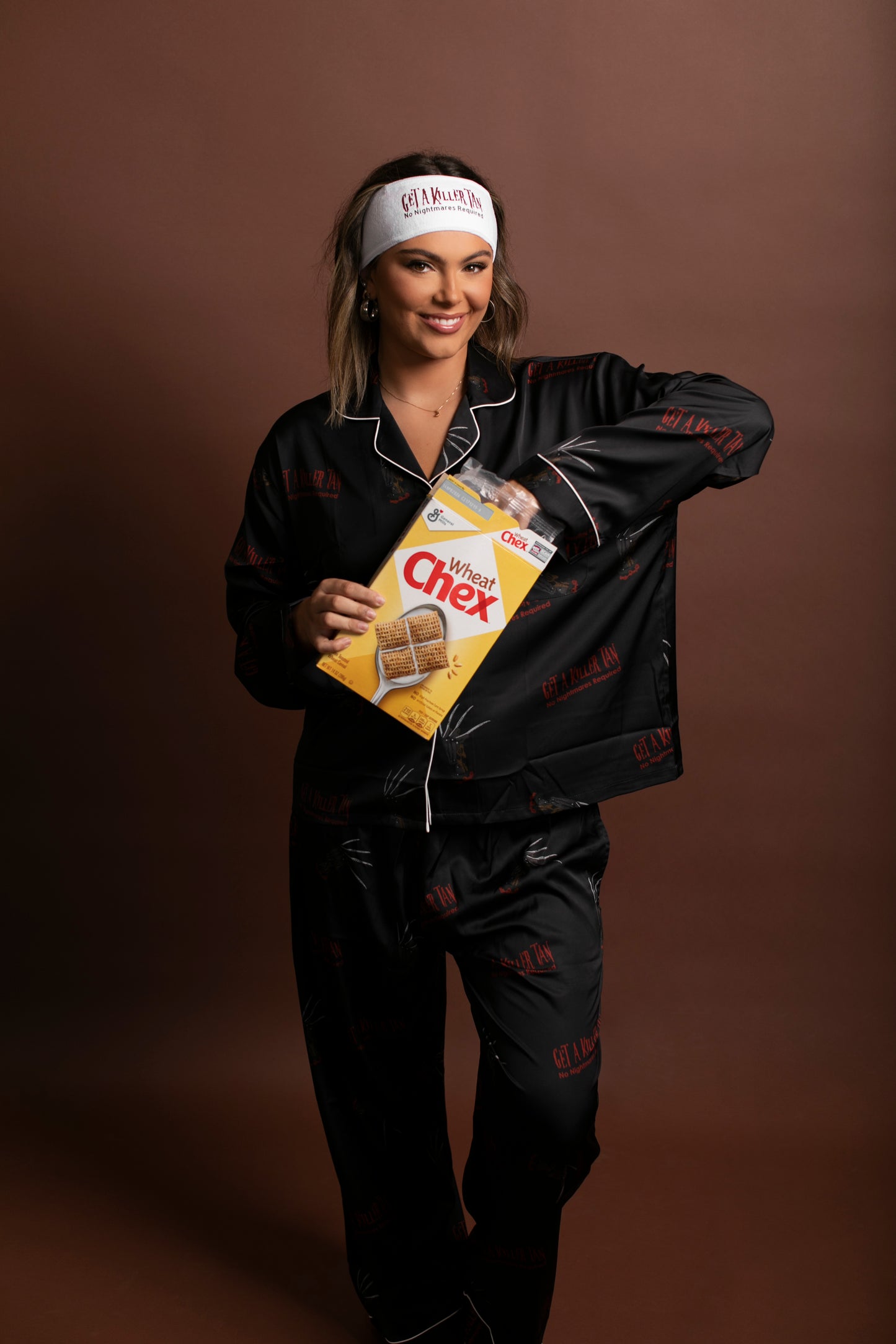 Person wearing a black outfit with a box of Chex cereal on a brown background