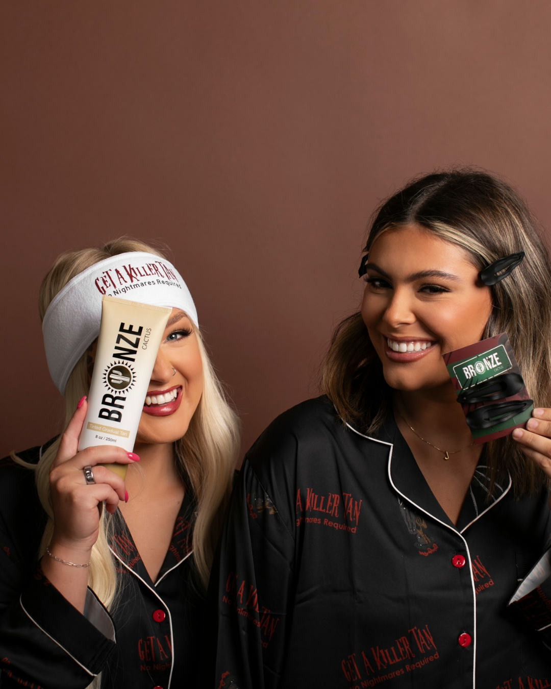 Two women in matching outfits holding bottles of 'Gila Miller' products against a brown background